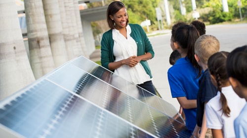 African American teacher in front of solar panels talking with students